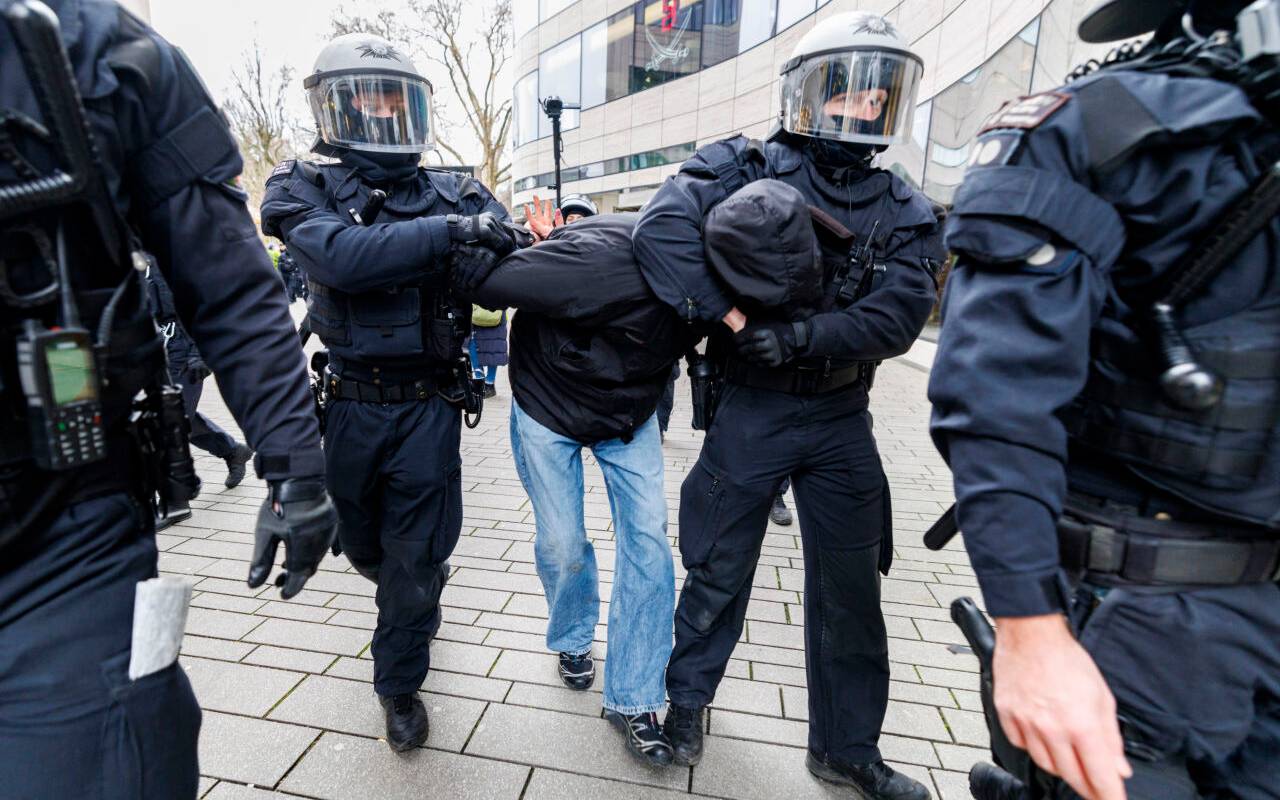 Polizeibeamte überwältigen einen Mann am Rande einer AFD-Kundgebung und Gegenprotesten.