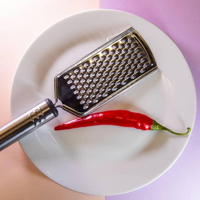 Chilischote liegt neben einer Küchenreibe