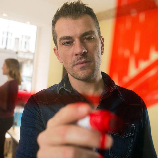 Mann malt zur Visualisierung einen Kreis an eine Plexiglasscheibe