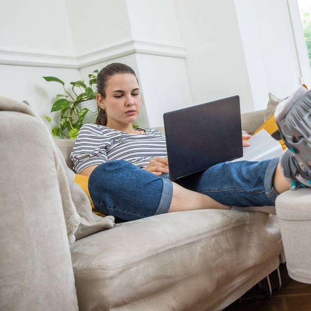 Eine Frau mit Fuß im Gips auf dem Sofa
