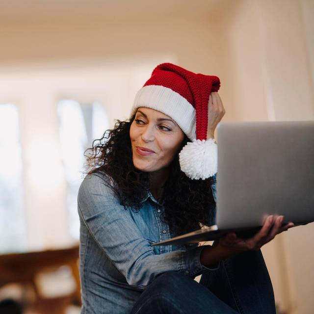 Eine Frau mit Weihnachtsmütze am Laptop