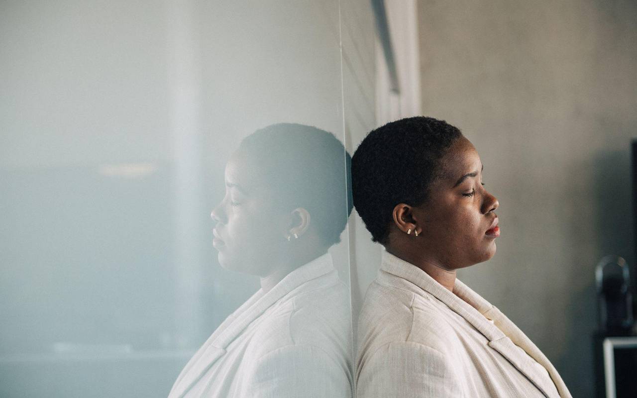 Eine junge Frau lehnt nachdenklich an einer Glaswand