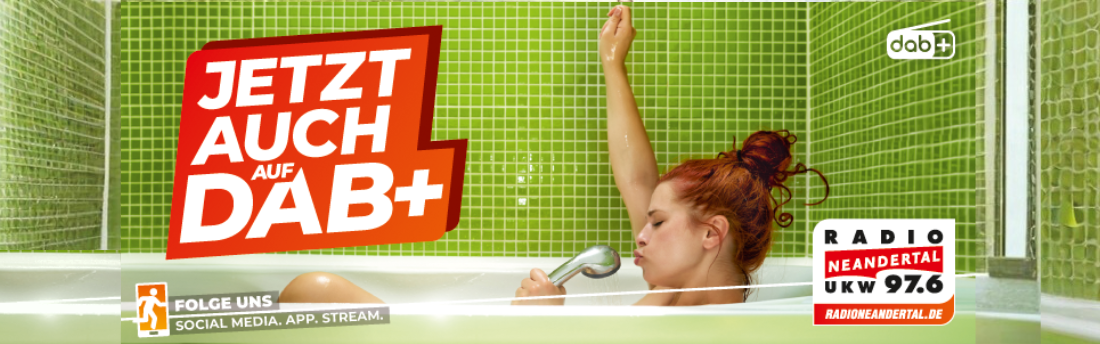 Eine Frau in der Badewanne nutzt den Brausekopf als Mikrofon und singt