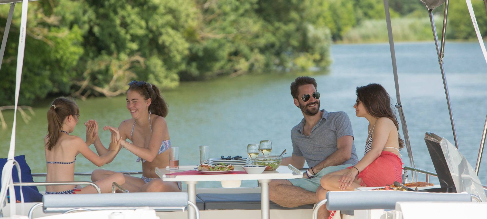 Familie macht, bei gutem Wetter, gemeinsam Urlaub auf einem Hausboot
