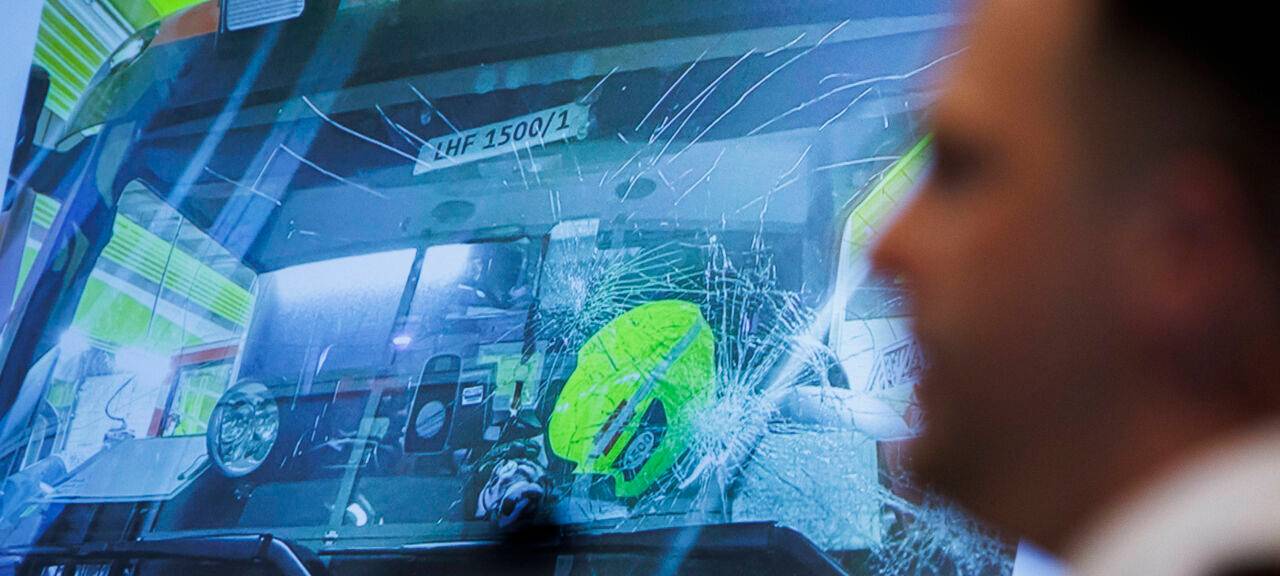 Ein Berliner Feuerwehrmann spricht vor der Darstellung eines beschädigten Feuerwehrwagens von seinen Erlebnissen in einer Silvesternacht.