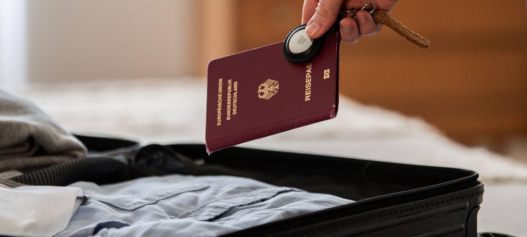 Eine Frau legt Airtag und Reisepass in einen Koffer