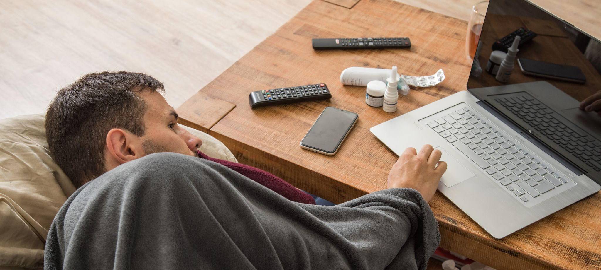 Ein Mann mit Erkältung bedient ein Laptop