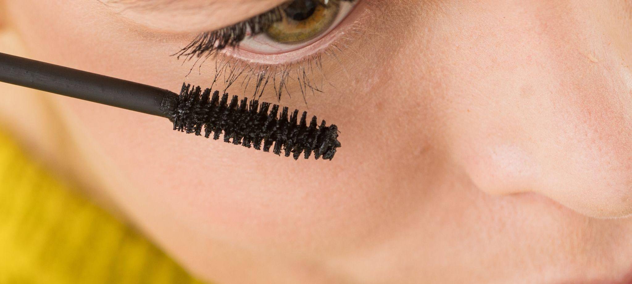 Eine Frau trägt Mascara auf ihre Wimpern auf