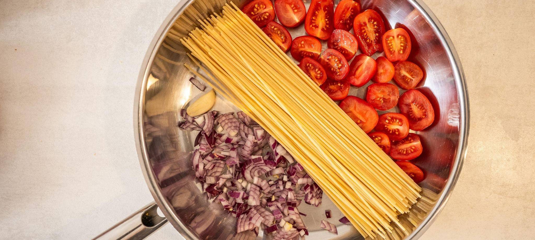 Spaghetti, Tomaten und Zwiebeln in einer Pfanne