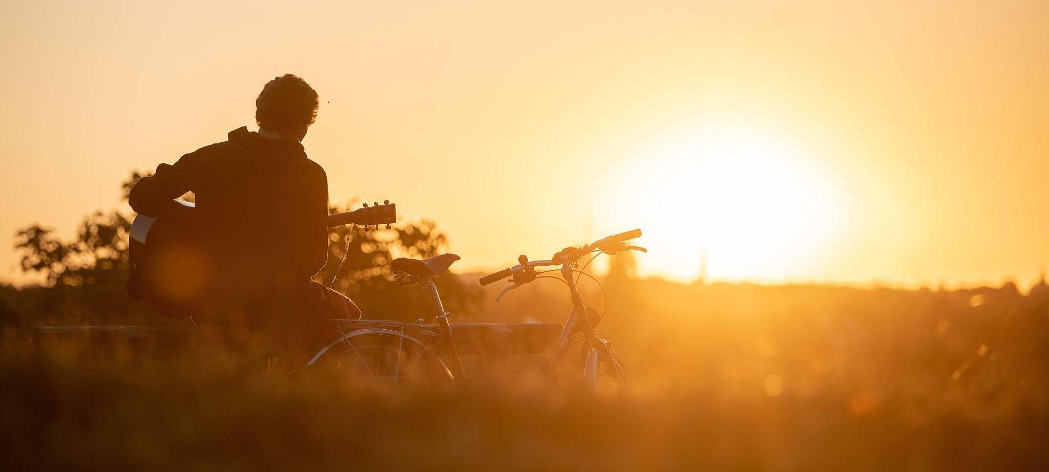 Mann spielt im Licht der aufgehenden Morgensonne Gitarre
